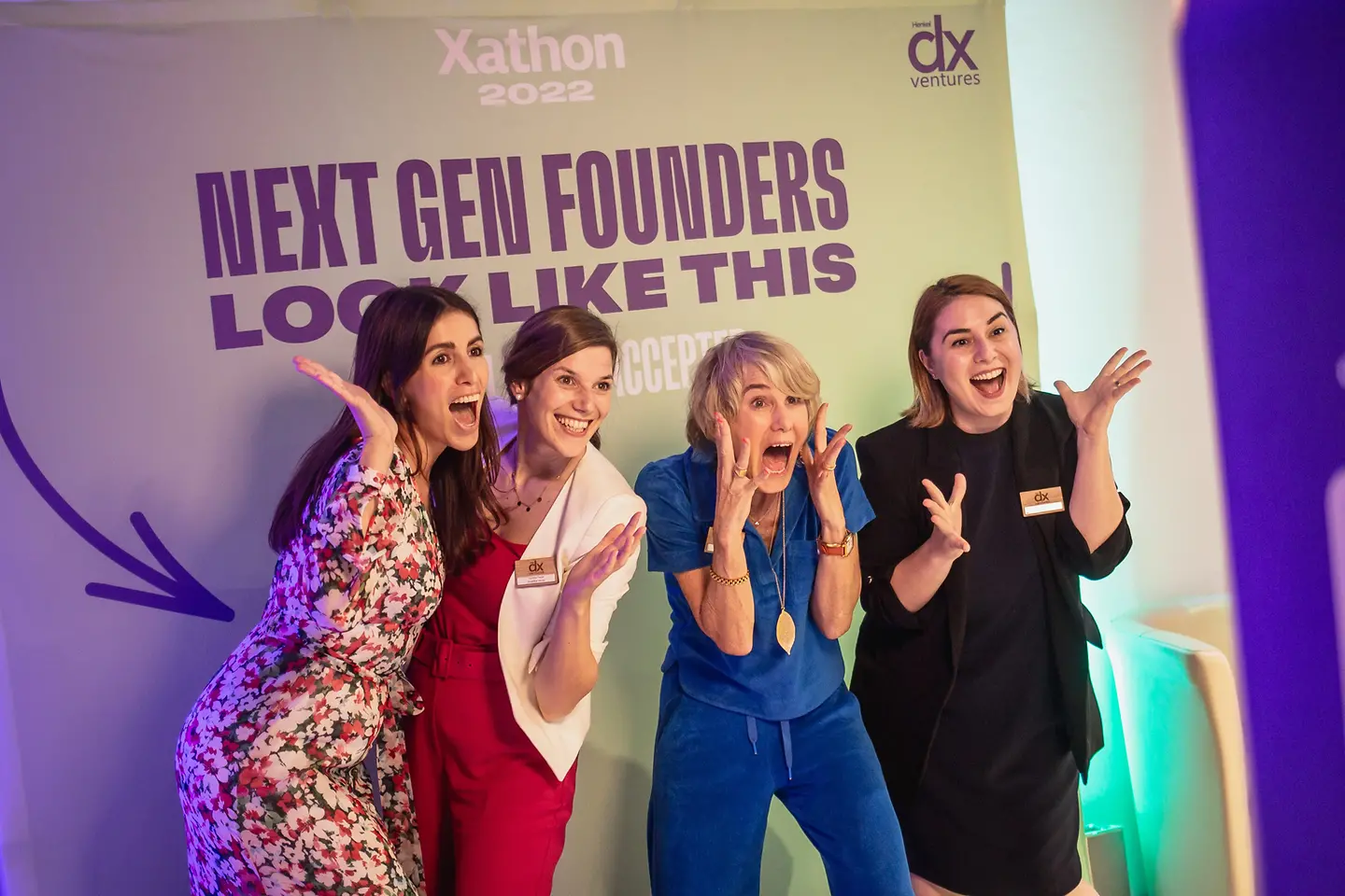 Four female entrepreneurs are standing in front of a photo wall which has 