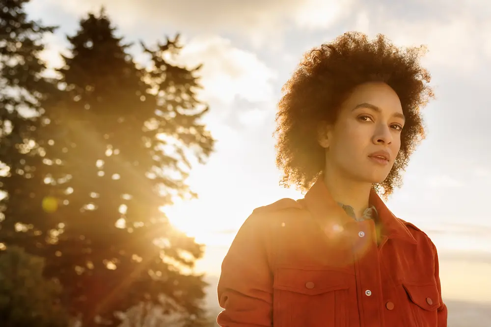 A confident woman stands in nature